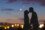 Silhouettes of a young couple kissing with city panorama in the background.